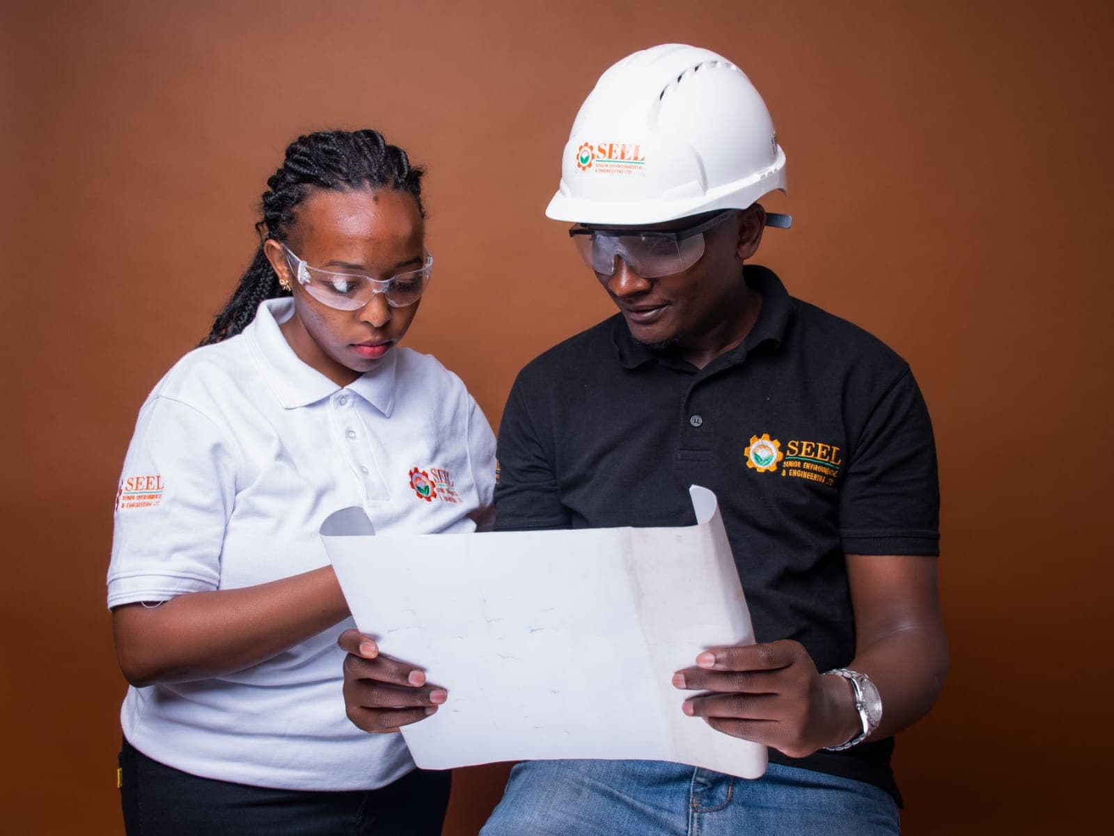 Two SEEL engineers in protective equipment reviewing a technical drawing